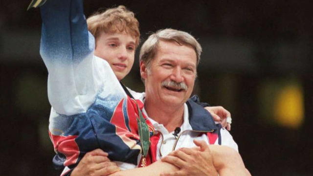 U.S. Olympic gymnastics coach Bela Karolyi carries injured gymnast Kerri Strug onto the podium after his team won the women's gold medal, July 23, 1996, in Atlanta. 