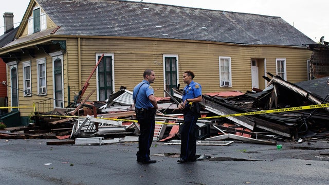 New Orleans Police officers stand in front of a collapsed building on the corner of North Claiborne Avenue and St. Philip Street after heavy rains and powerful winds hit in New Orleans, La., Aug. 4, 2016. 
