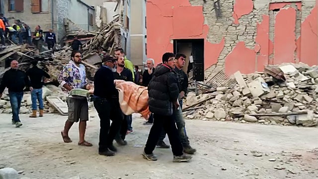 This still image taken from video shows rescuers recover a victim from a crumbled building in Amatrice 