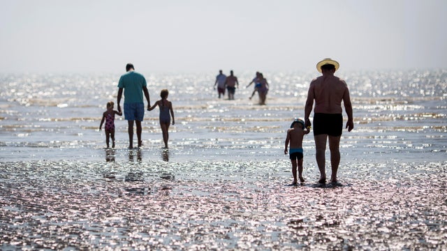 Beachgoers walk toward the sea on Camber Sands on Aug. 25, 2016, in Rye, England. 