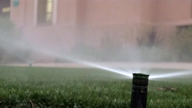 A sprinkler sprays water onto fake grass outside a Los Angeles Department of Water and Power facility. 