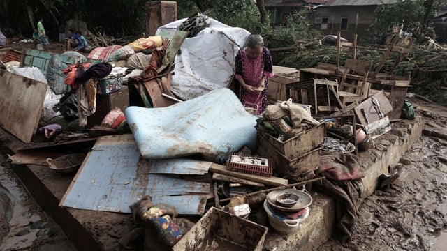 An Indonesian woman stands amid salvaged belongings after flash floods hit Kamulyan village in Banyumas, Central Java 
