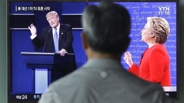 A man watches a TV screen showing the live broadcast of the U.S. presidential debate between Democratic presidential nominee Hillary Clinton and Republican presidential nominee Donald Trump 