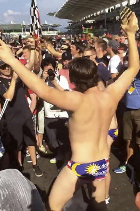 An Australian man dances in a Budgy Smuggler-brand swimsuit decorated with the Malaysian flag at the conclusion of the Malaysian Formula One Grand Prix in Sepang 
