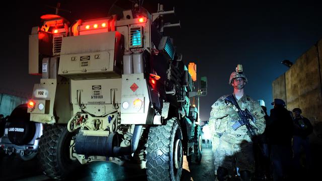 A U.S. soldier and Afghan security forces stand next a military vehicle 