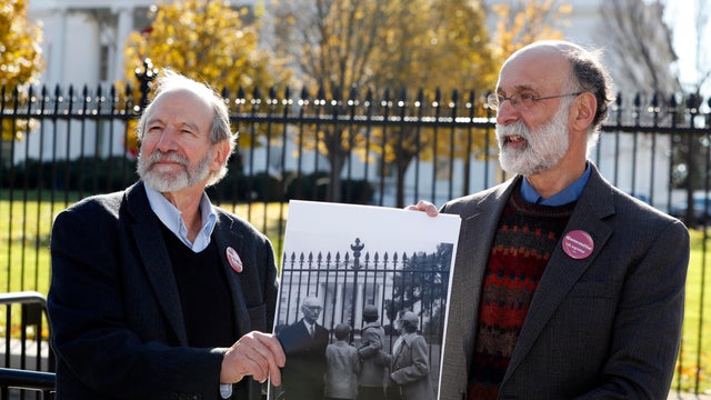 Michael, left, and Robert Meeropol, the sons of Ethel Rosenberg, pose with an old photograph of them before they attempt to deliver a letter to President Obama seeking an exoneration of their mother, Dec. 1, 2016, in Washington. 