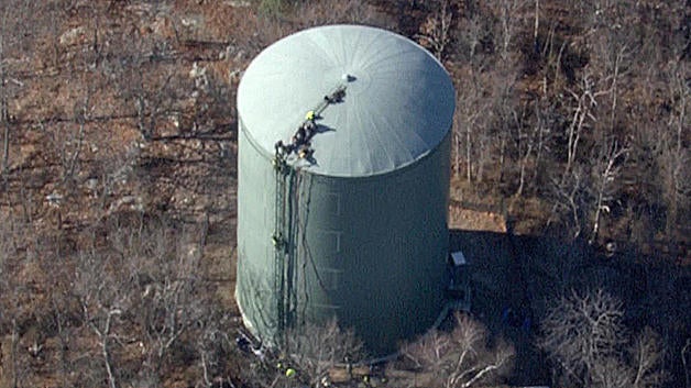 Rescuers climb atop a water tank in Braintree, Massachusetts, after two workers became trapped on Dec. 15, 2016. 