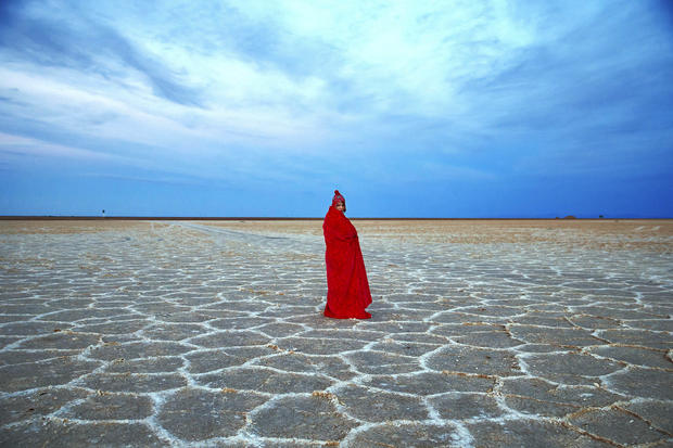 An Iranian woman covers herself with a blanket due to the cold while visiting Khour salt lake during her tour of the Mesr desert about 305 miles southeast of the capital Tehran Dec. 1, 2016. Deserts make up parts of Iran which have recently become tourist 