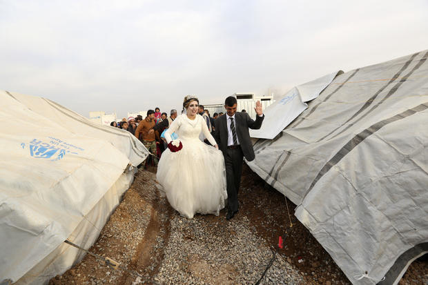 Iraqi internally displaced groom Jassim Mohammed walks with his bride, Amena Ali, during their wedding ceremony at a camp for internally displaced people, in Khazir, near Mosul, Iraq, Dec. 8, 2016. 