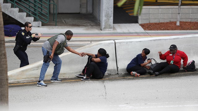 Police assist people seeking cover outside of Terminal 2 at Fort Lauderdale-Hollywood International Airport after a shooting took place in the baggage claim area on Jan. 6, 2017, in Fort Lauderdale, Florida. 