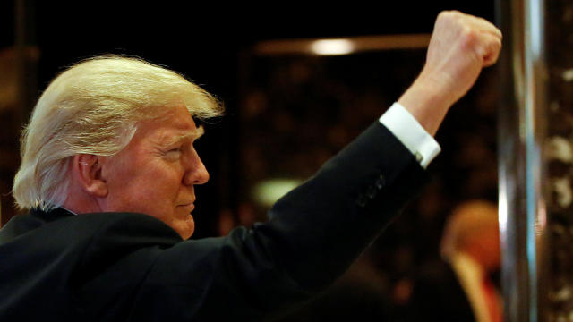 President-elect Donald Trump gestures to people in the lobby after speaking to the news media with television personality Steve Harvey and businessman Greg Calhoun after their meeting at Trump Tower in New York Jan. 13, 2017. 