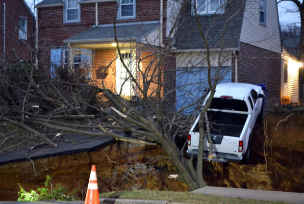 A pickup truck dangles over the edge of a sinkhole that swallowed parts of two residential yards Jan. 25, 2017, in the Philadelphia suburb of Glenside, Pa. 