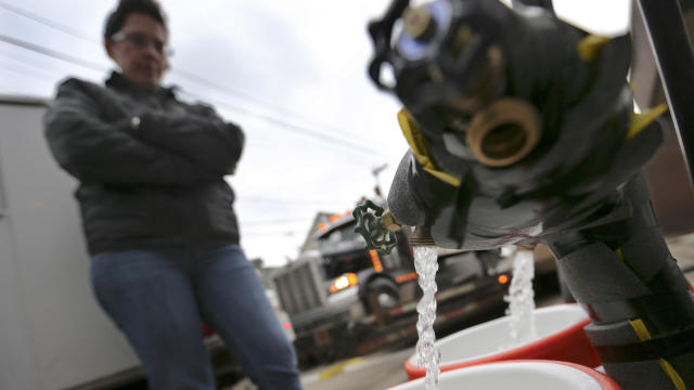 Ronette Cooley watches as she fills containers with water at a city fire station in the Lawrenceville section of Pittsburgh, where water buffaloes are available for the public on Feb. 1, 2017. 