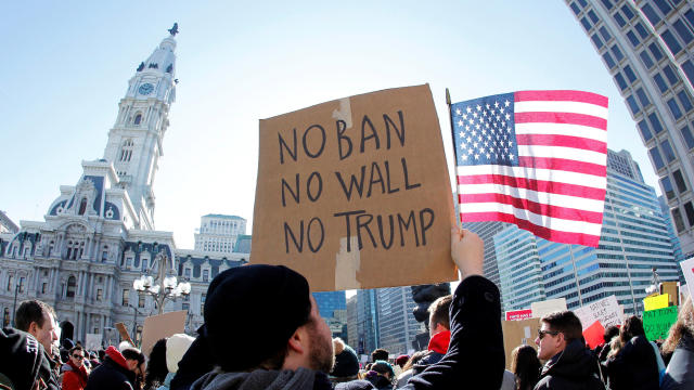 Protester Brandon McTear holds a sign and the American flag as demonstrators gather to protest against President Trump’s executive order banning refugees and immigrants from seven primarily Muslim countries from entering the United States during a rally i 