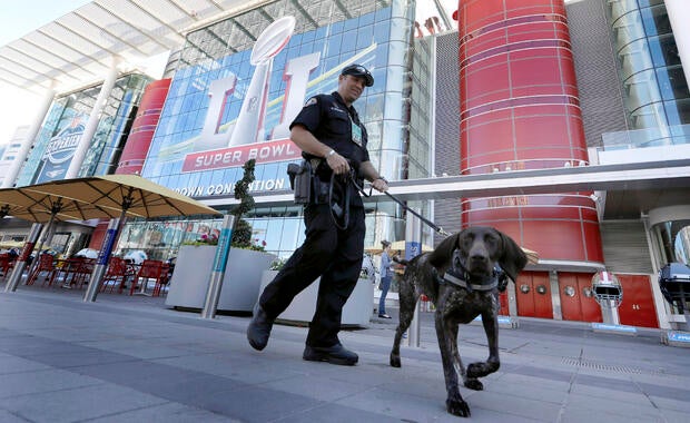 Officer Keith McCart, of the Long Beach, Calif., Police Department, patrols with K-9 Pidura outside the George R. Brown Convention Center, the NFL Super Bowl 51 football media center and site of the NFL Experience, Jan. 31, 2017, in Houston.