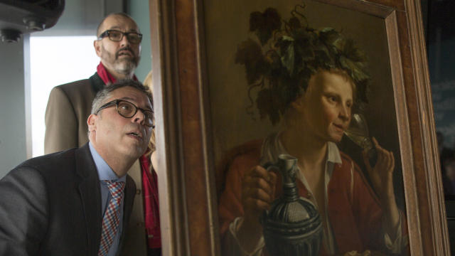 Dr. Clarence Epstein, foreground, director of the Max Stern Art Restitution Project, inspects the back of “Young Man As Bacchus” by Jan Franse Verzijl during a ceremony to formally return the painting to representatives of the Max and Iris Stern Foundatio 