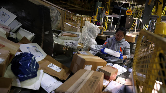 A U.S. postal worker sorts packages at the U.S. post office distribution center on Dec. 19, 2016, in Richmond, California. 