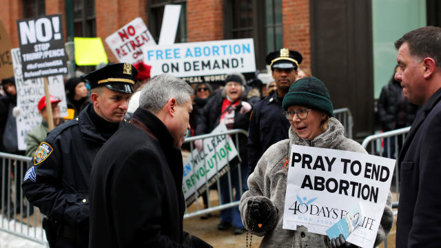 An anti-Planned Parenthood protester walks by pro-abortion-rights protesters gathered outside the Planned Parenthood - Margaret Sanger Health Center in Manhattan, New York, Feb. 11, 2017. 