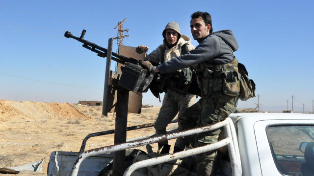 Syrian government forces stand in the back of an armed vehicle as they approach the strategic Jihar oil fields on the eastern outskirts of Homs on Feb. 7, 2017. 