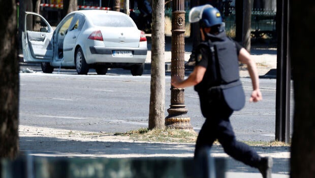 A French gendarme runs past a car on the Champs-Elysees after an incident in Paris, France, June 19, 2017.