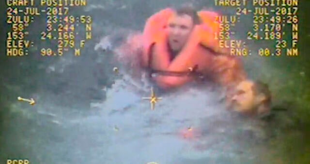 The captain of the fishing vessel Grayling, left, rescues one of his crewmen after the vessel capsized in the Kupreanof Strait near Raspberry Island, Alaska, in this still image from video taken on July 24, 2017, by the Coast Guard. 