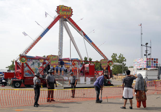 Passers-by look at the Fire Ball ride as Ohio State Highway Patrol troopers stand guard at the Ohio State Fair July 27, 2017, in Columbus, Ohio. 