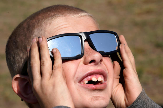 Cooper Jackson tries out his new solar glasses in a designated eclipse viewing area in a campground near Guernsey 