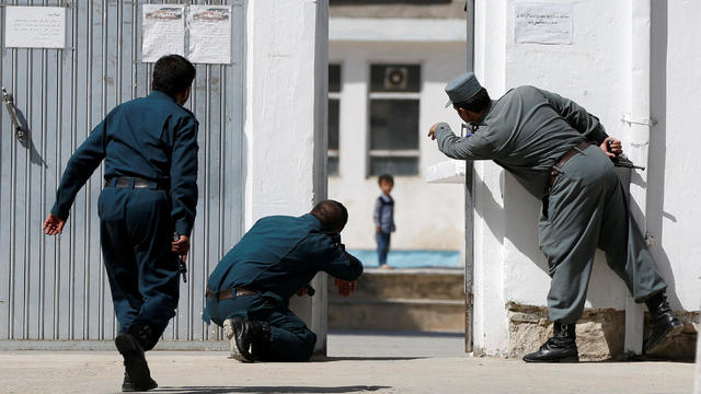 Afghan policemen try to rescue a child at the site of a suicide attack followed by a clash between Afghan forces and insurgents after an attack on a Shi'ite Muslim mosque in Kabul 