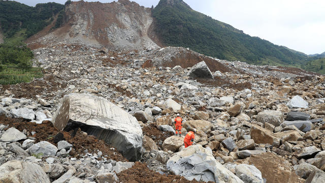 Rescue workers search for survivors at the site of a landslide that occurred in Nayong county 