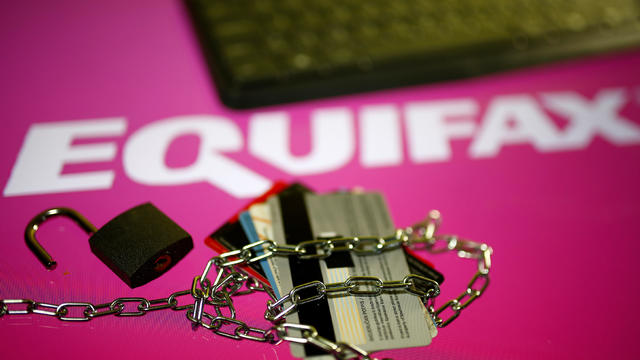 Credit cards, a chain and an open padlock is seen in front of displayed Equifax logo in this illustration 