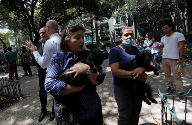 Women carrying their dogs stand outside their homes after an earthquake in Mexico City 