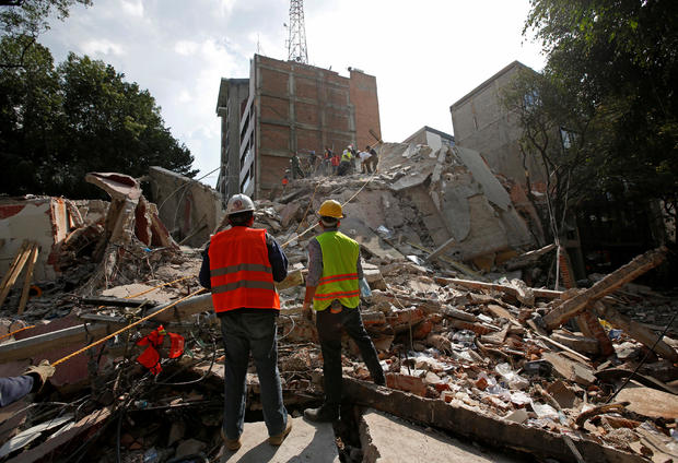 Rescue workers look at fellow workers searching for people under the rubble of a collapsed building after an earthquake hit Mexico City, Mexico 