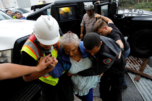 Rescue workers help a woman to get into the Emergency Operation Centre after the area was hit by Hurricane Maria in Guayama 