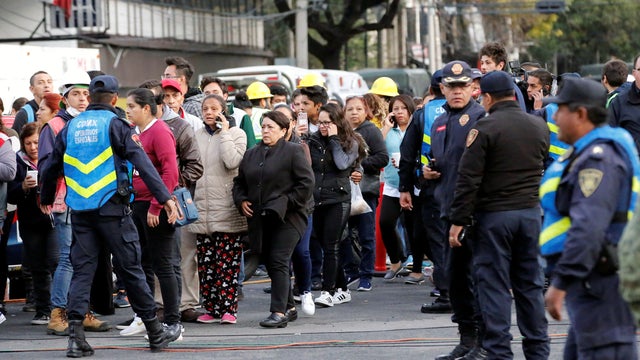Police officers and people wait along the street after a tremor was felt in Mexico City 