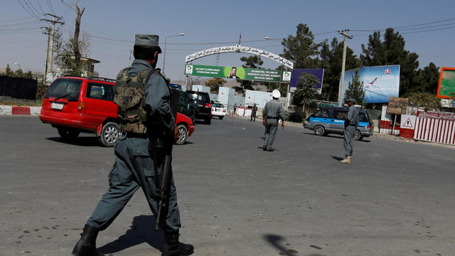 Afghan policemen stand guard outside of Kabul Airport after rockets exploded in Kabul, Afghanistan 