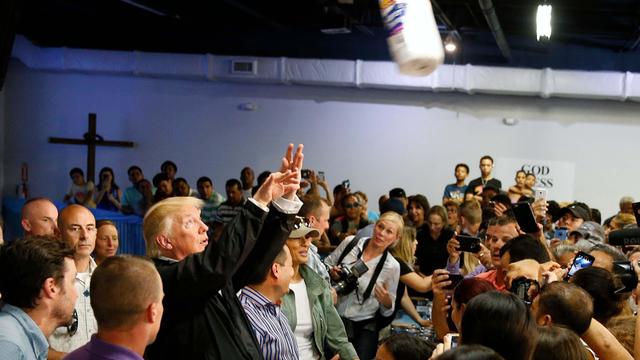 President Trump throws a roll of paper towels to residents gathered in a chapel while visiting areas damaged by Hurricane Maria in San Juan, Puerto Rico 
