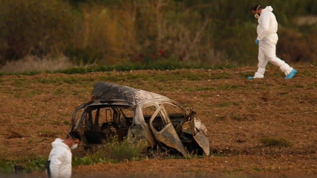 Forensic experts walk in a field after a powerful bomb blew up a car killing investigative journalist Daphne Caruana Galizia in Bidnija 