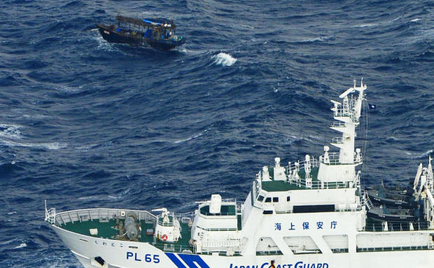 A Japan Coast Guard vessel sails near a drifting wooden boat carrying men identified as North Koreans off Matsumae on the northern Japanese island of Hokkaido, in this photo taken by Kyodo Nov. 29, 2017. 