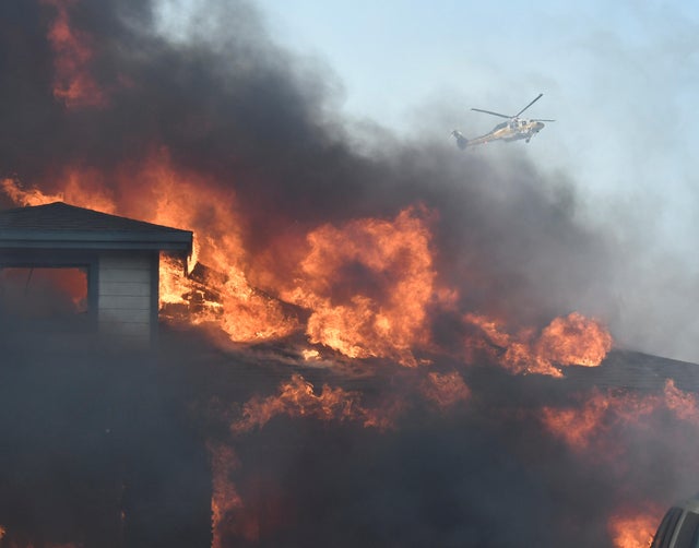 A firefighting helicopter tries to make a water drop in heavy winds after an early-morning Creek Fire that broke out in the Kagel Canyon area in the San Fernando Valley north of Los Angeles