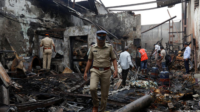 Policemen and rescue workers inspect the debris at a damaged site after a fire broke out at a snack factory in Mumbai 