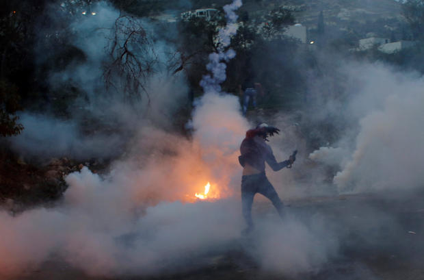 Palestinian demonstrator hurls back a tear-gas canister fired by Israeli troops during clashes at a protest near the West Bank city of Nablus 
