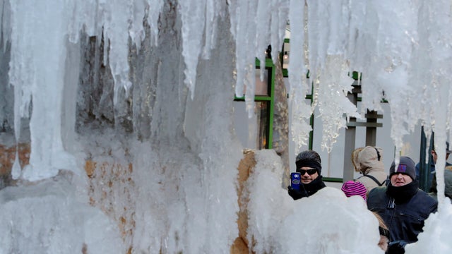 Pedestrians stop to photograph the frozen Josephine Shaw Lowell Memorial Fountain in New York 