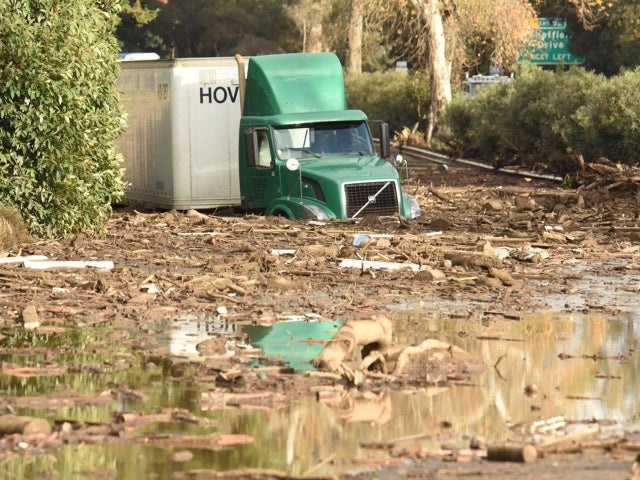 A semi-tractor trailer sits stuck in mud and flood waters on the highway after mudslides in Montecito