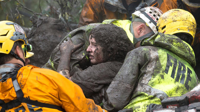 Emergency personnel carry a woman rescued from a collapsed house after a mudslide in Montecito 