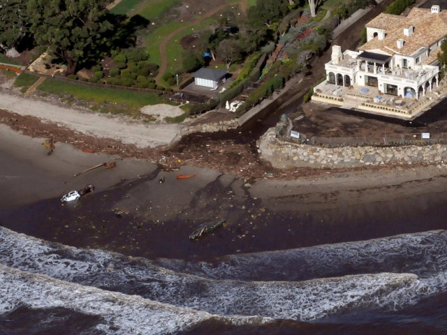 An aerial photo showing two vehicles submerged in the surf amidst debris from a mudslide due to heavy rains in Montecito