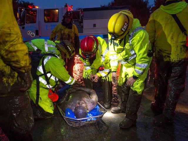 Emergency personnel carry a man covered in mud after a mudslide in Montecito