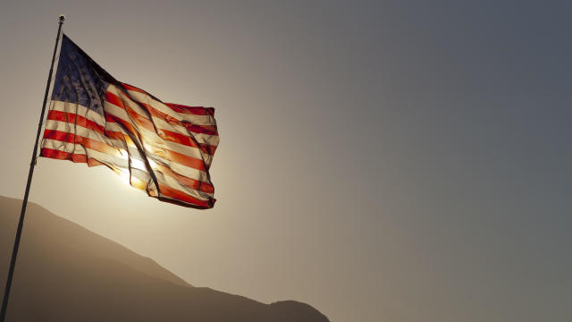 Back-lit American flag flying on pole with copy space. 