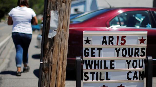 A pedestrian walks past a sign reading "AR15 Get Yours While You Still Can" outside the IDC Firearms gun shop in Clinton 