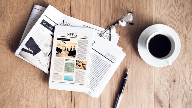 Newspaper with tablet on wooden table 