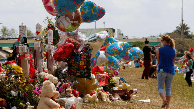 A visitor views memorials on crosses on the grounds of Marjory Stoneman Douglas High School in Parkland 